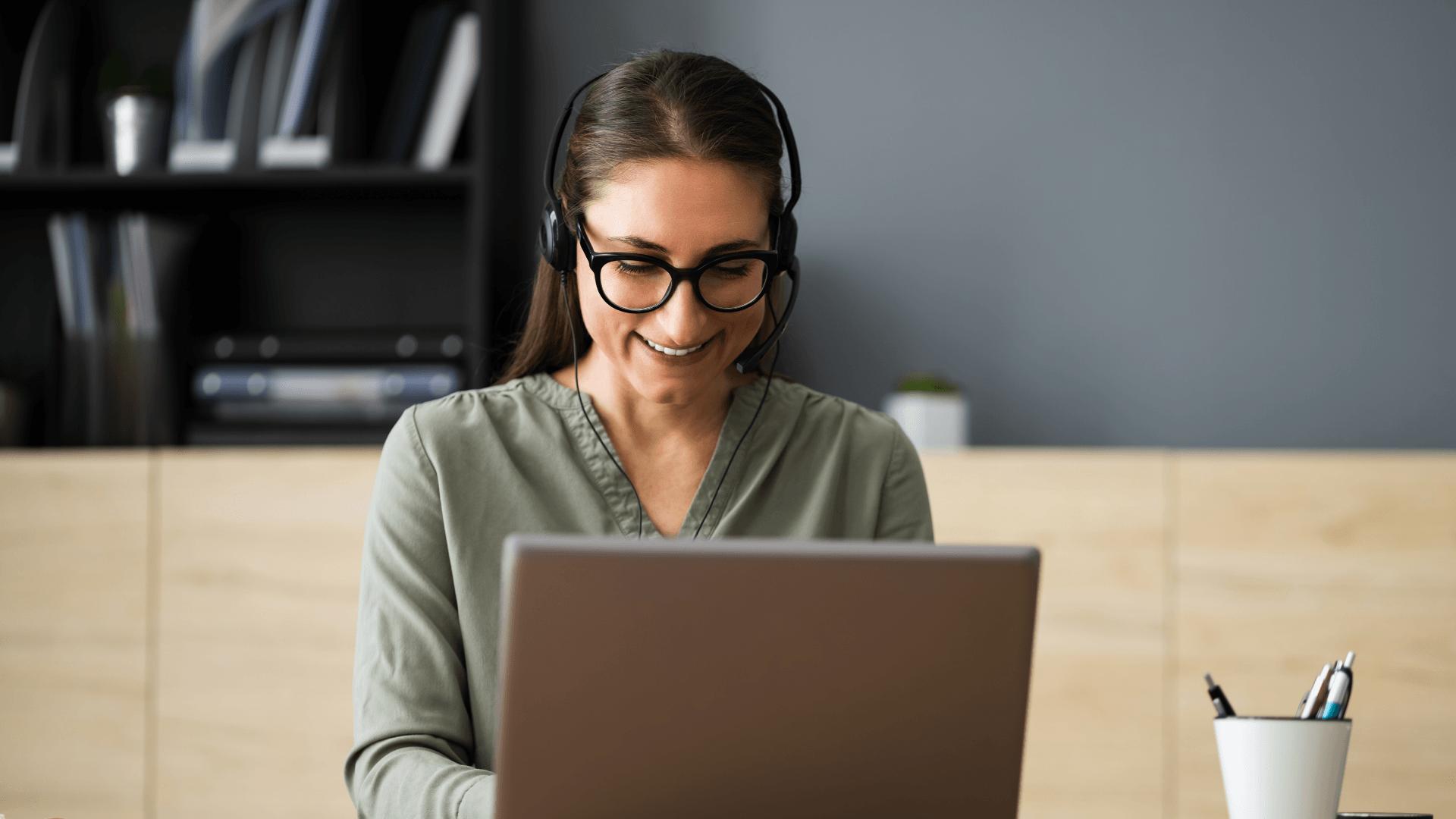 A Virtual Assistant wearing headphones is sitting in front of a laptop computer.