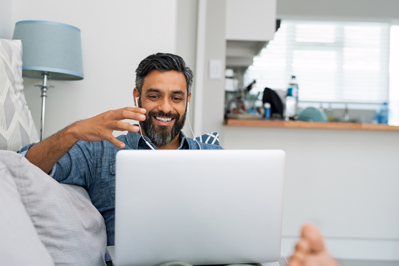 A Virtual Assistant is sitting on a couch using a laptop computer.