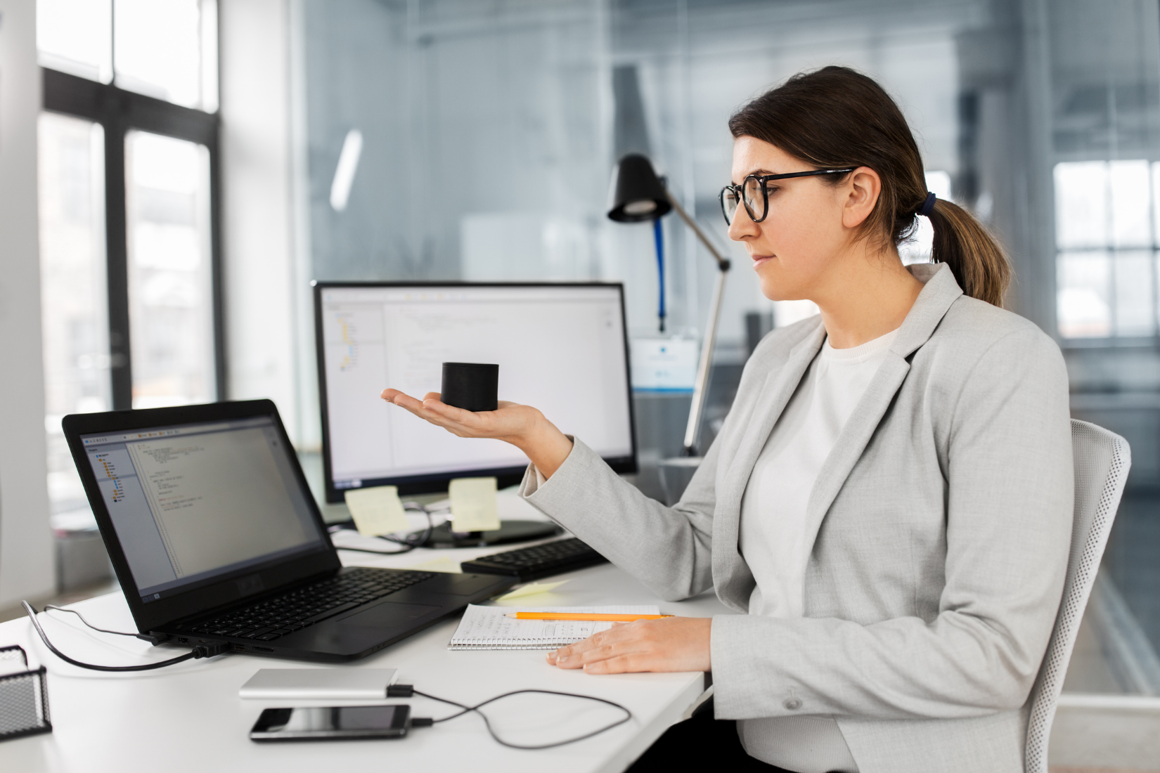A Virtual Assistant is sitting at a desk with a laptop and a cell phone.