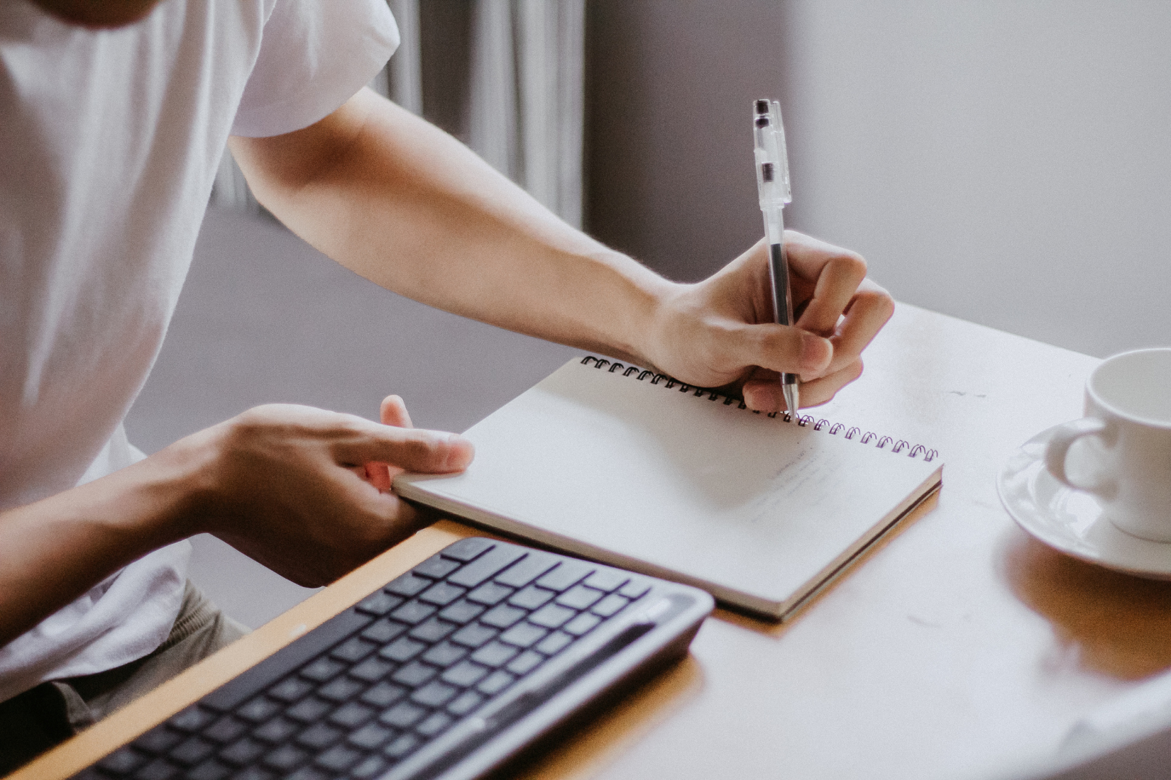 A Virtual Assistant is sitting at a desk writing in a notebook.