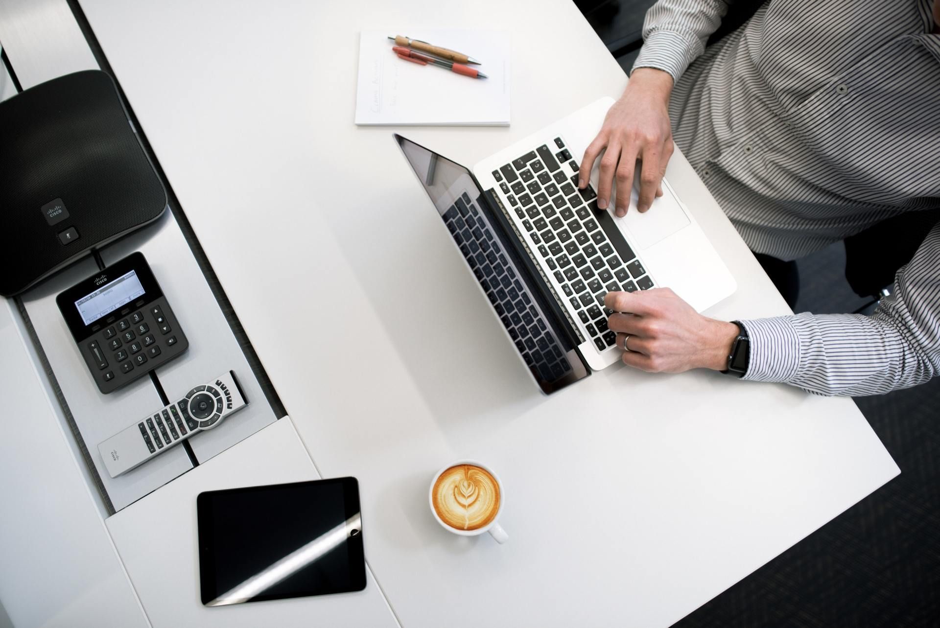 A Virtual Assistant is sitting at a desk using a laptop computer.
