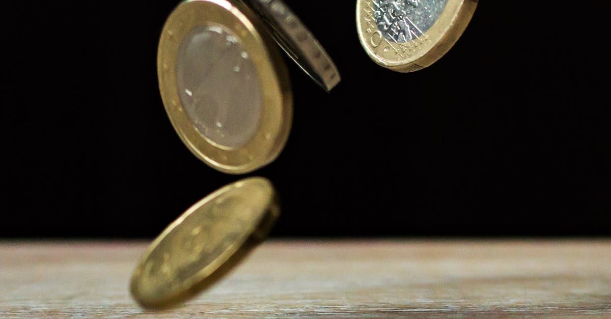 A bunch of coins are falling on a wooden table.