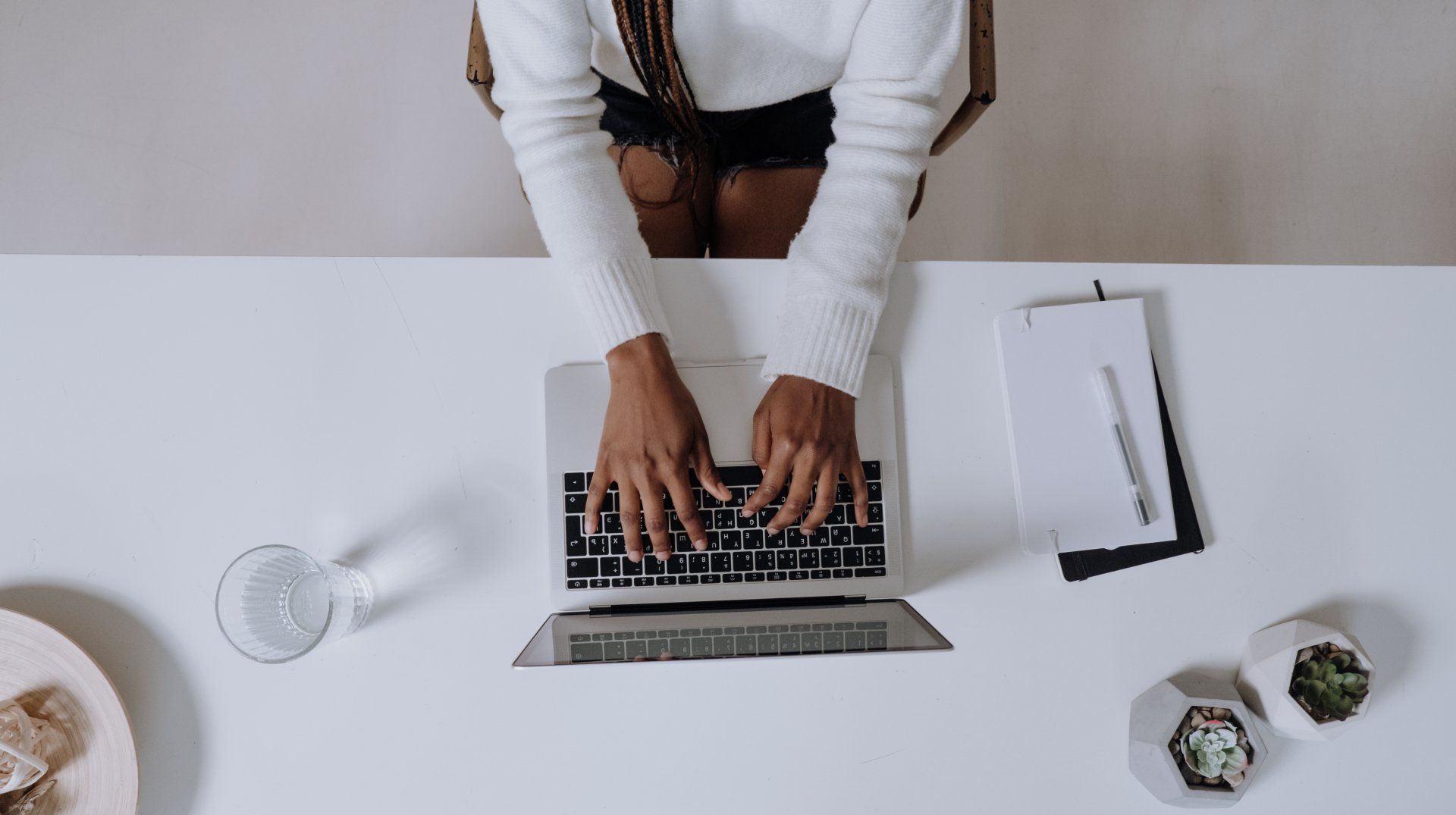 A Virtual Assistant is sitting at a desk typing on a laptop computer.