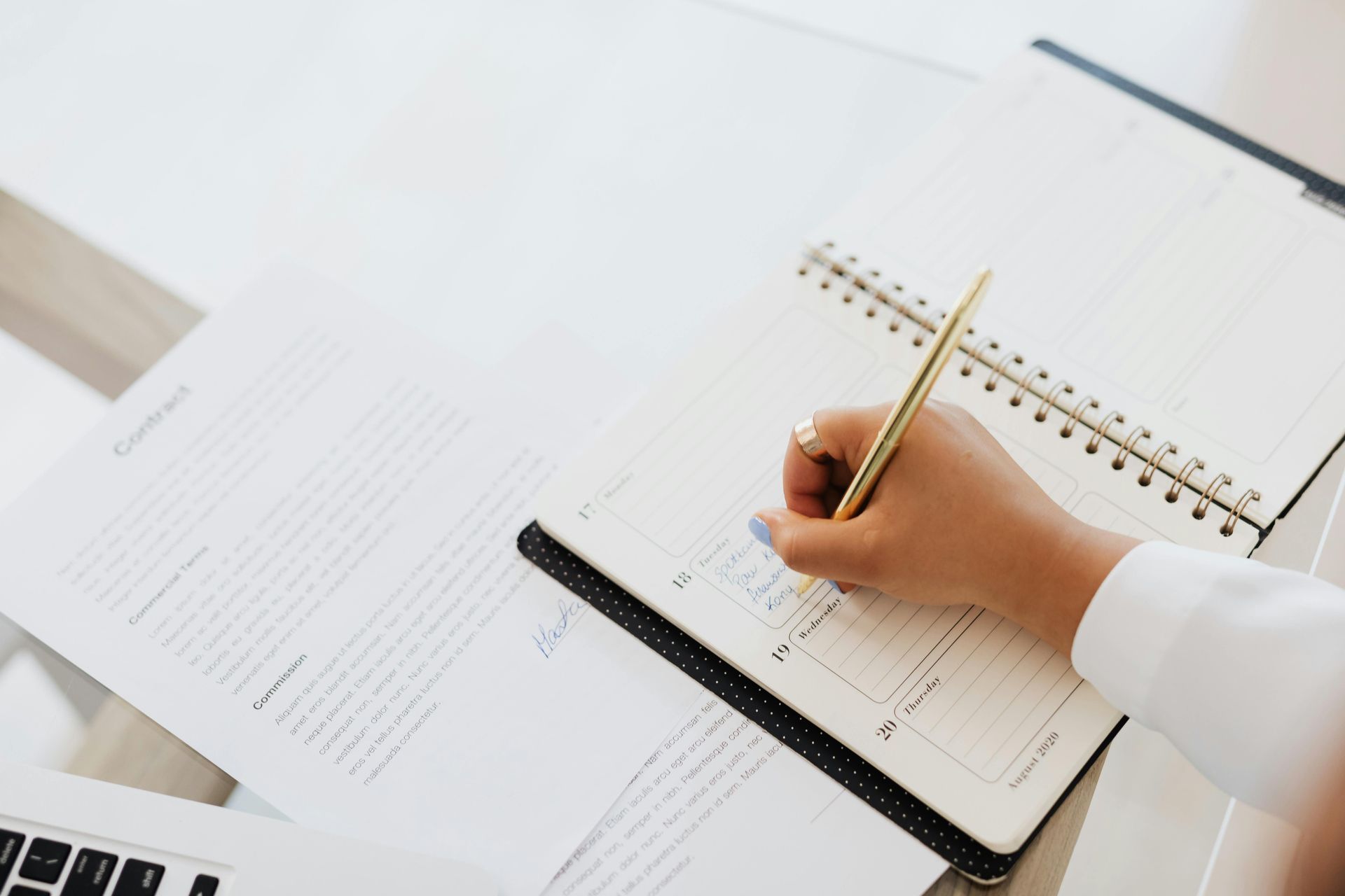 A person is writing in a notebook with a pen.