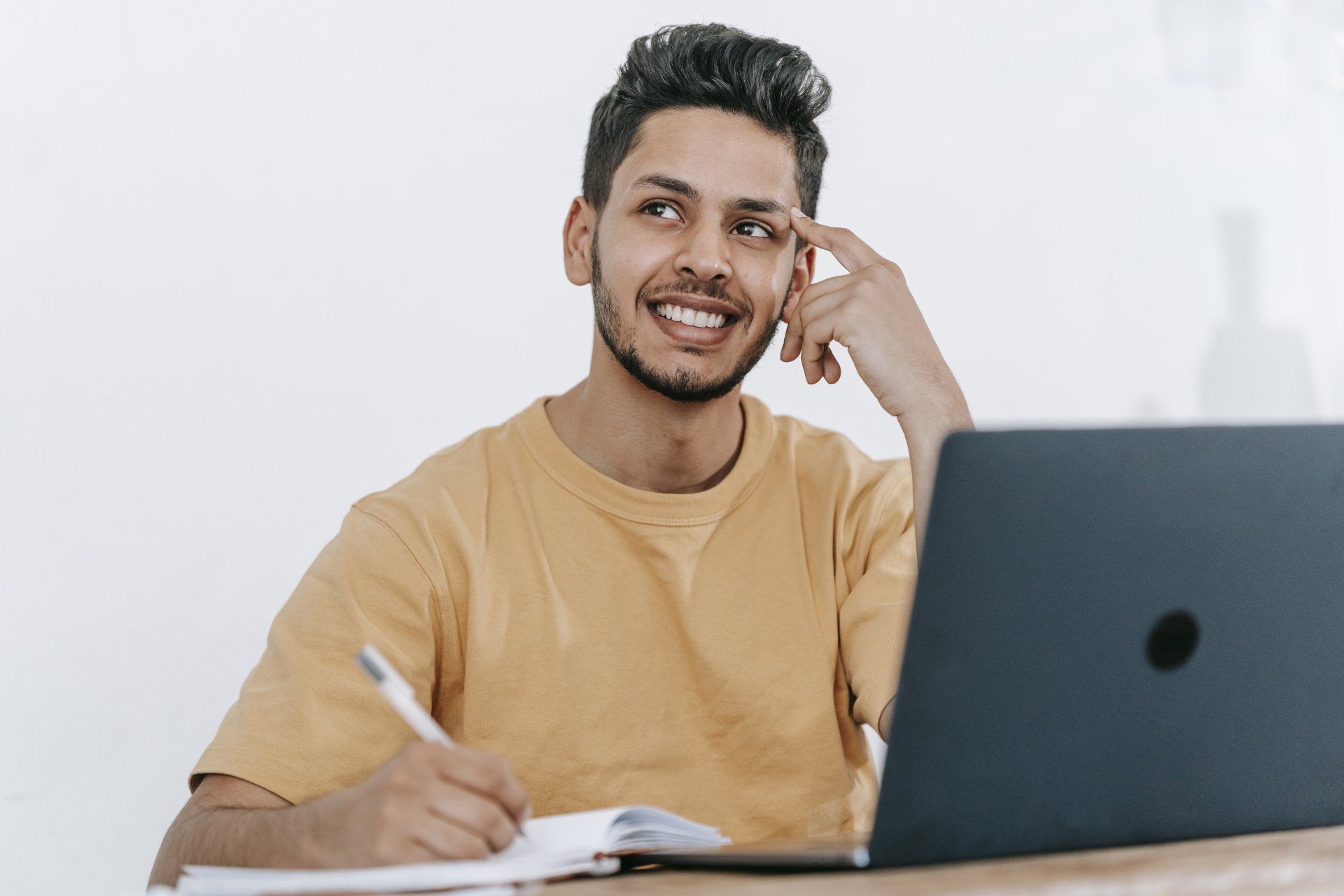 A Virtual Assistant is sitting at a desk with a laptop and a notebook.