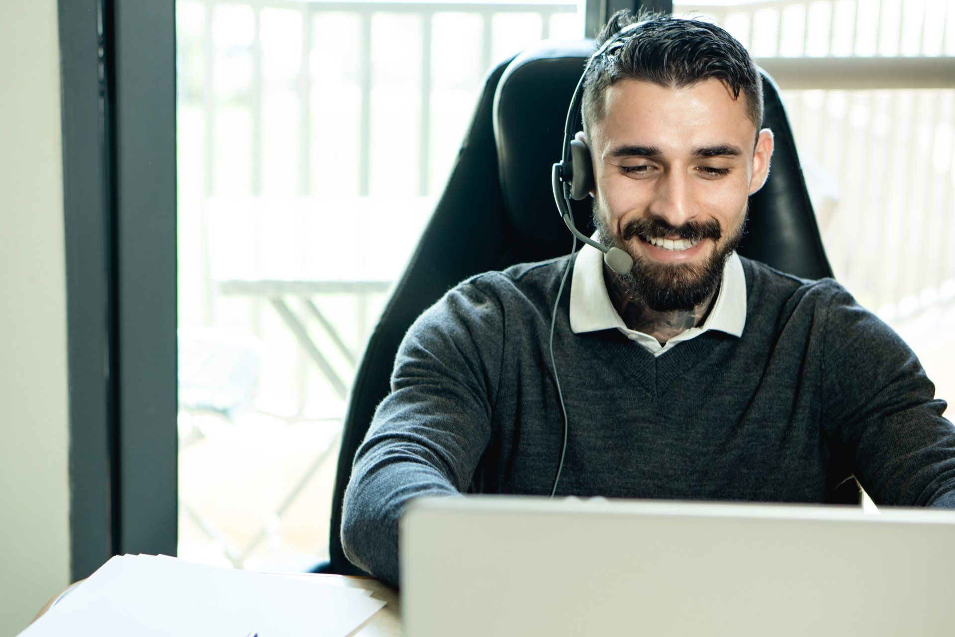 A Virtual Assistant wearing a headset is sitting in front of a laptop computer.