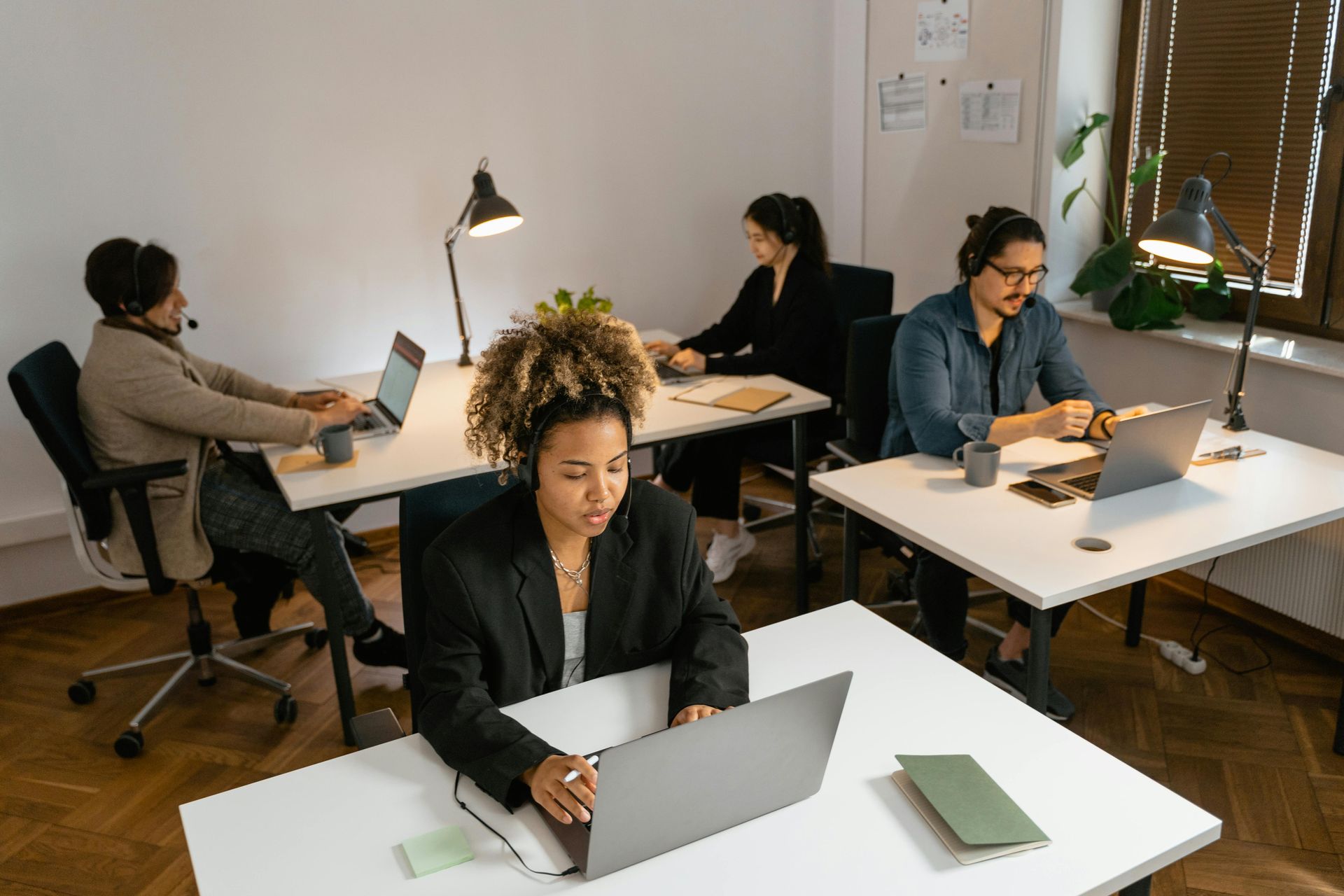 People working at desks with laptops in a bright office.
