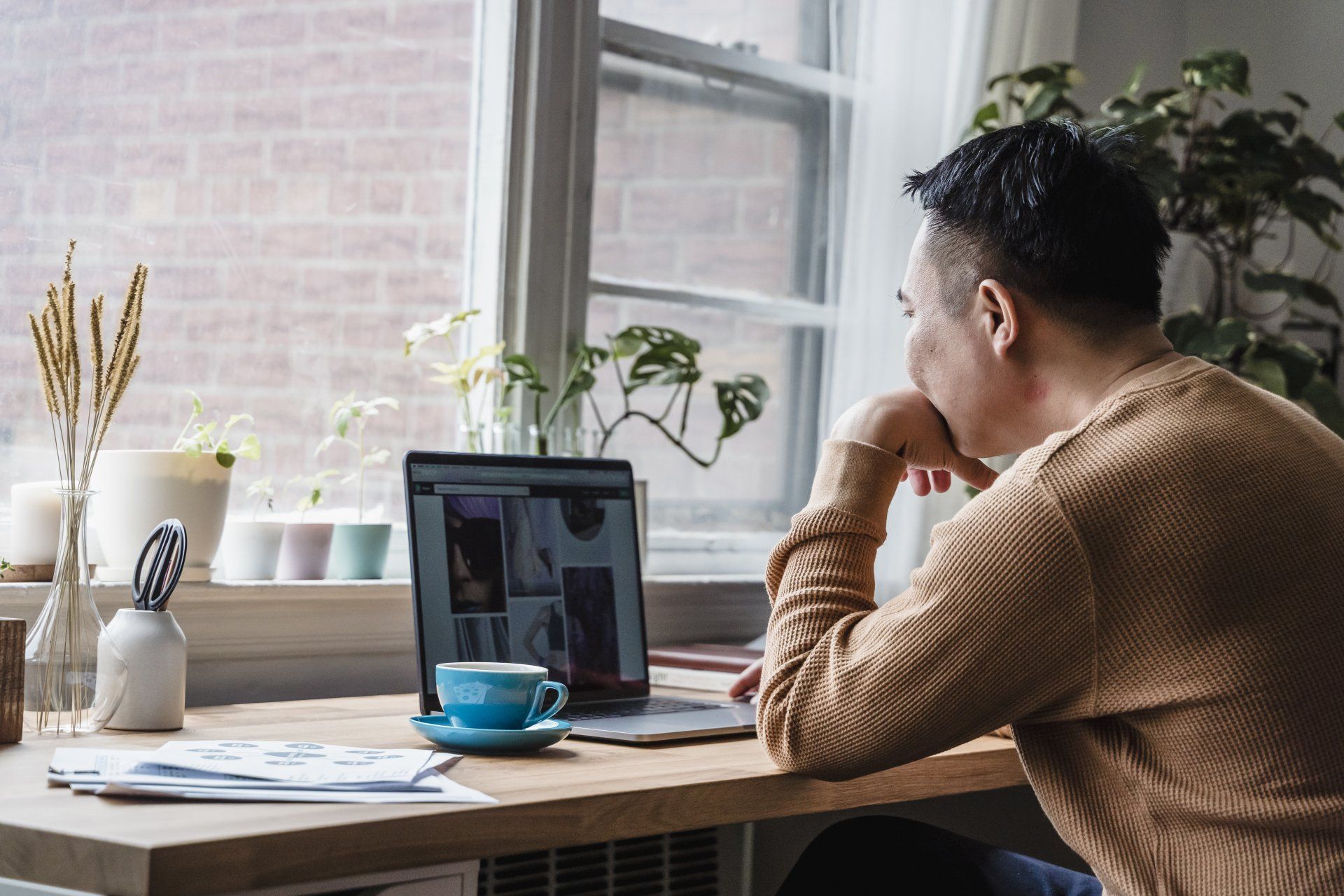 A Virtual Assistant is sitting at a table with a laptop and a cup of coffee.