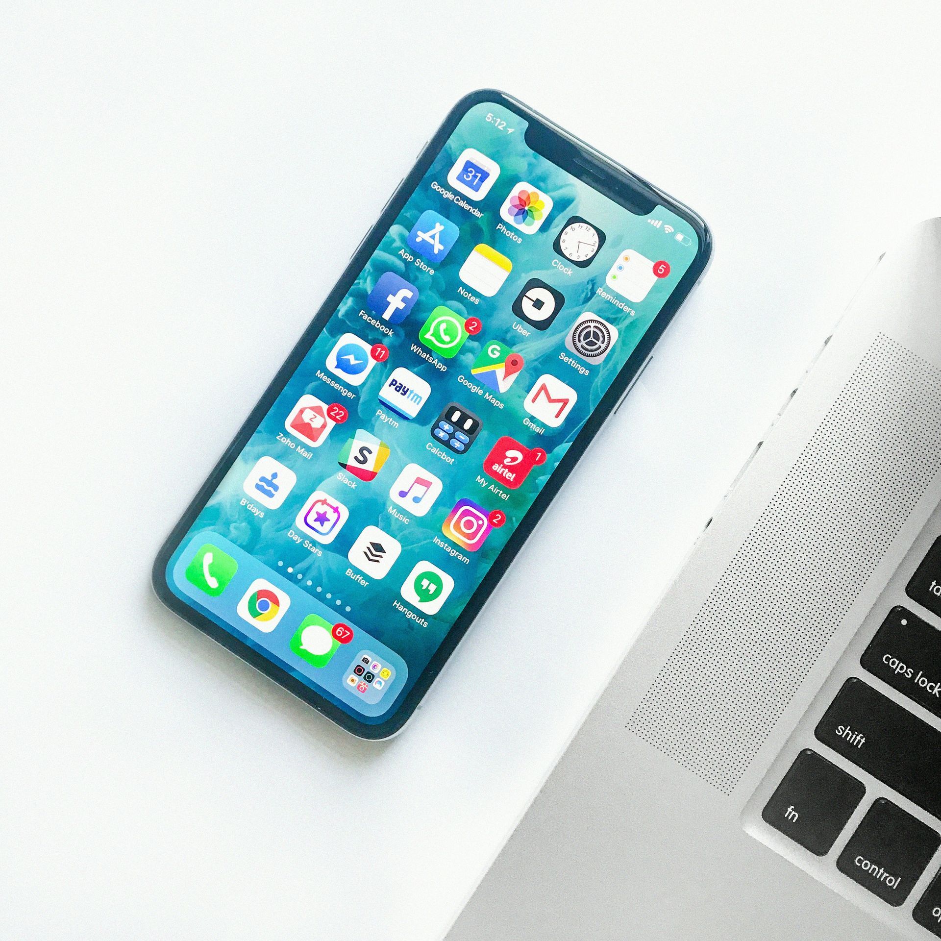 A cell phone is sitting next to a laptop on a table.