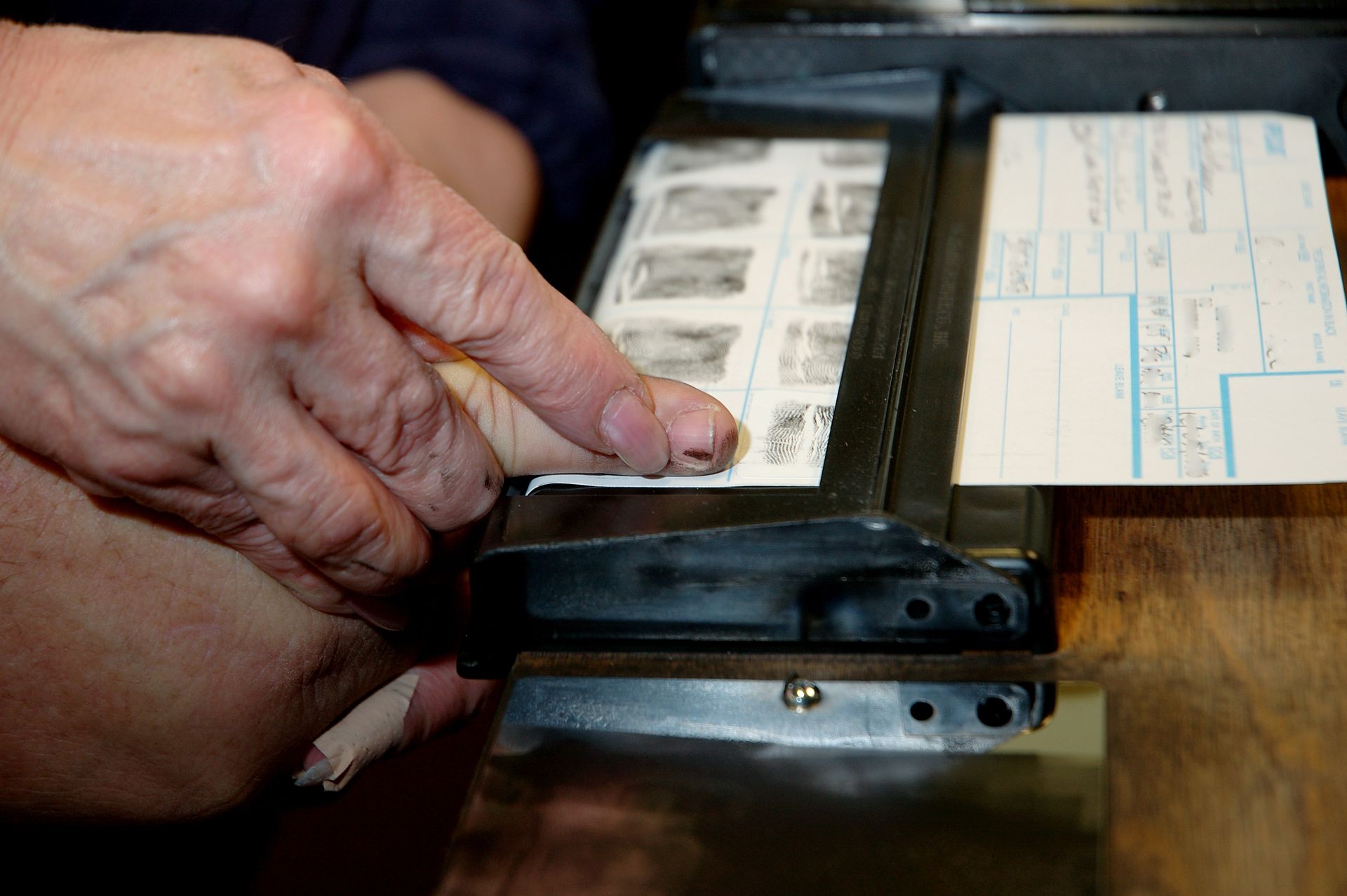 Person's hand using a paper cutter to trim a strip of film negatives next to a form.