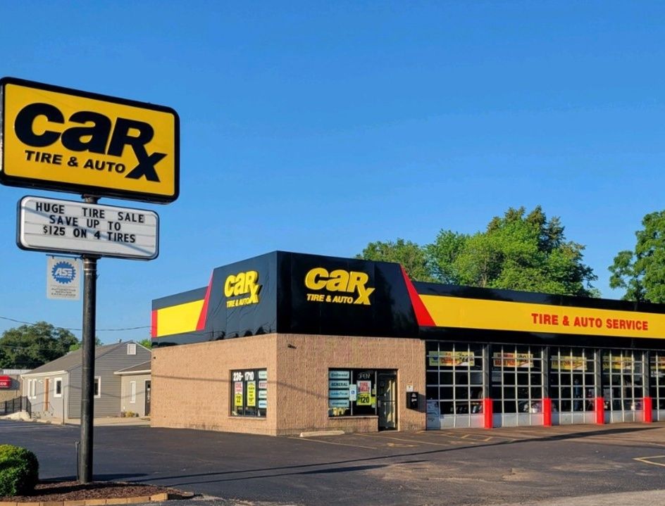 CarX Tire & Auto Service building with a sign advertising a tire sale under a clear sky.