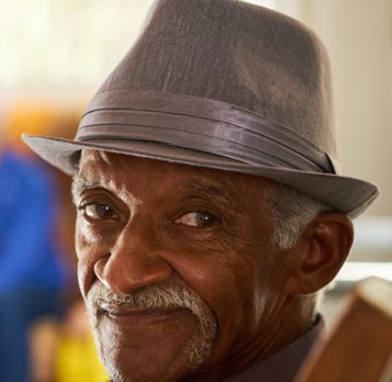 Elderly man with a gray fedora and mustache looking at the camera with a slight smile.