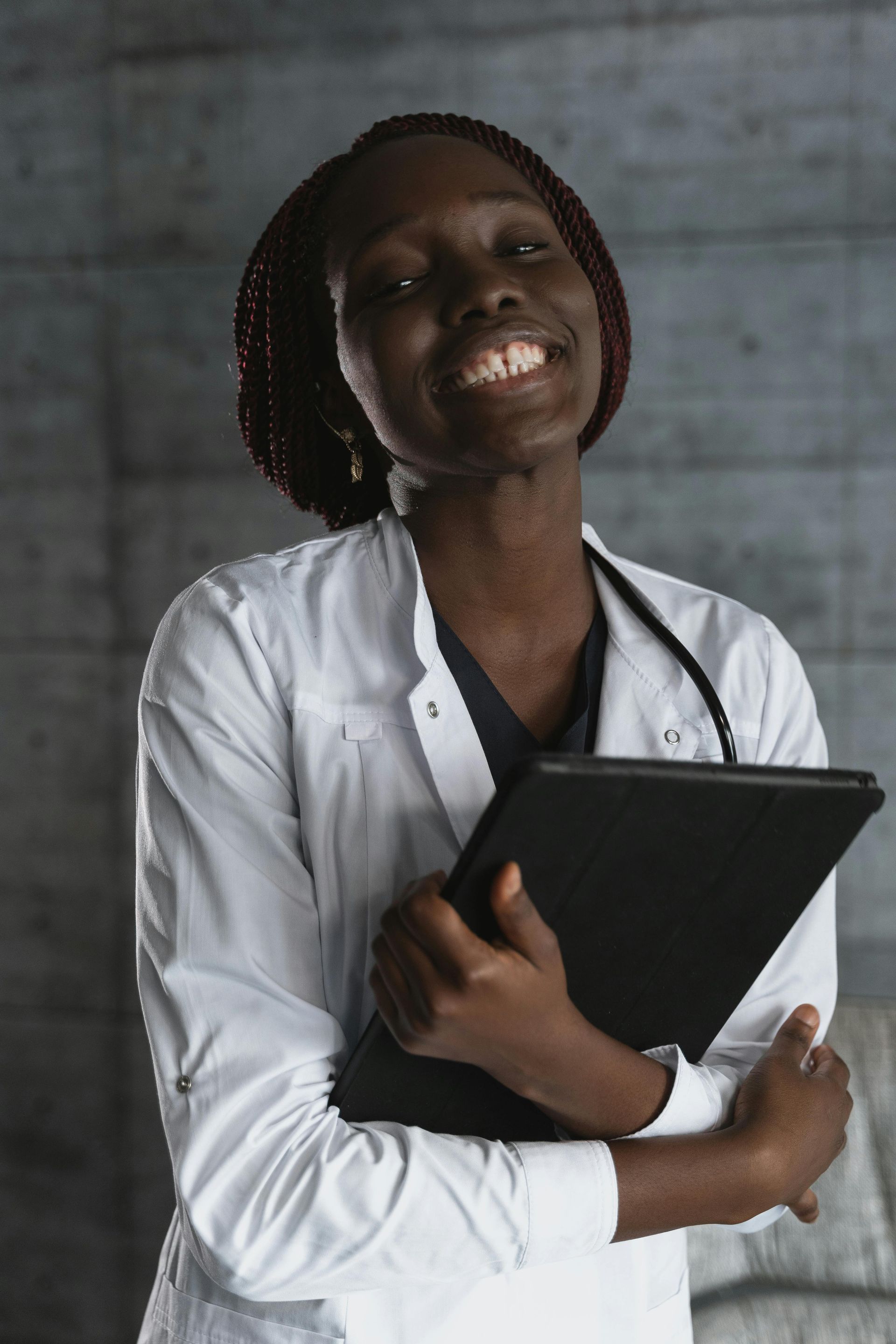 Woman with short hair, wearing a white shirt and apron, smiles in front of a plant.