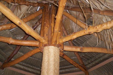 A wooden structure with a thatched roof and a tree in the middle.