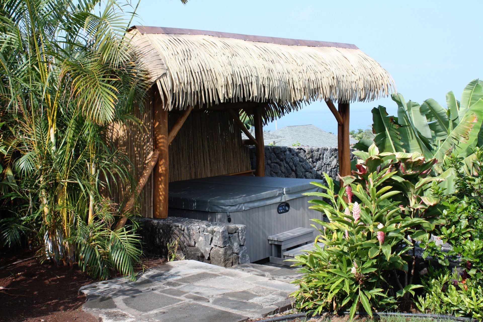 A thatched gazebo with a hot tub underneath it
