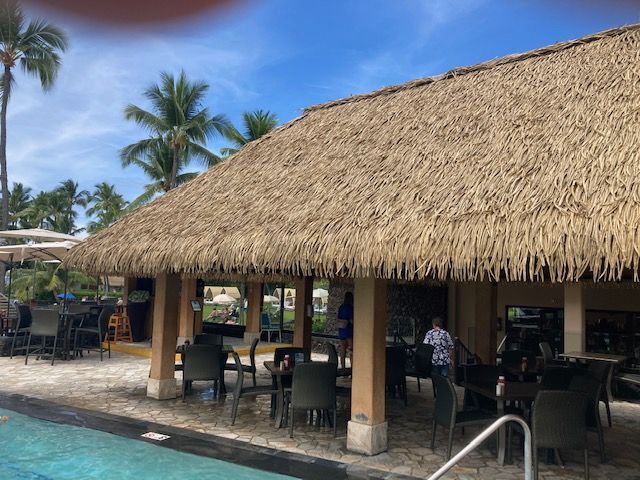 A thatched roofed building next to a swimming pool