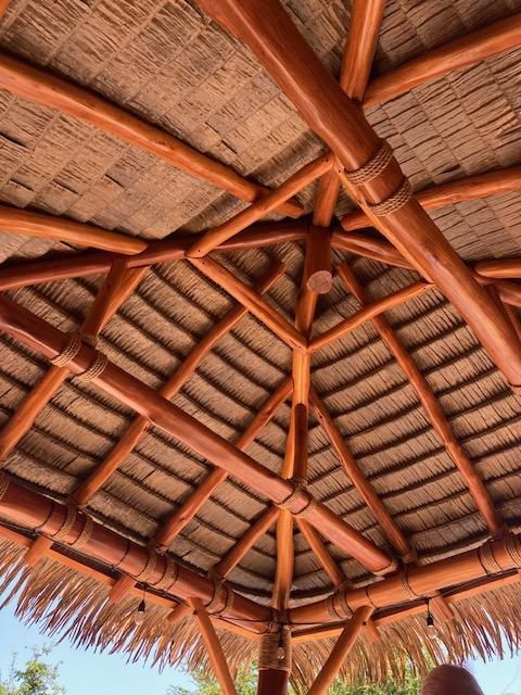 The ceiling of a gazebo made of wood and thatched straw.