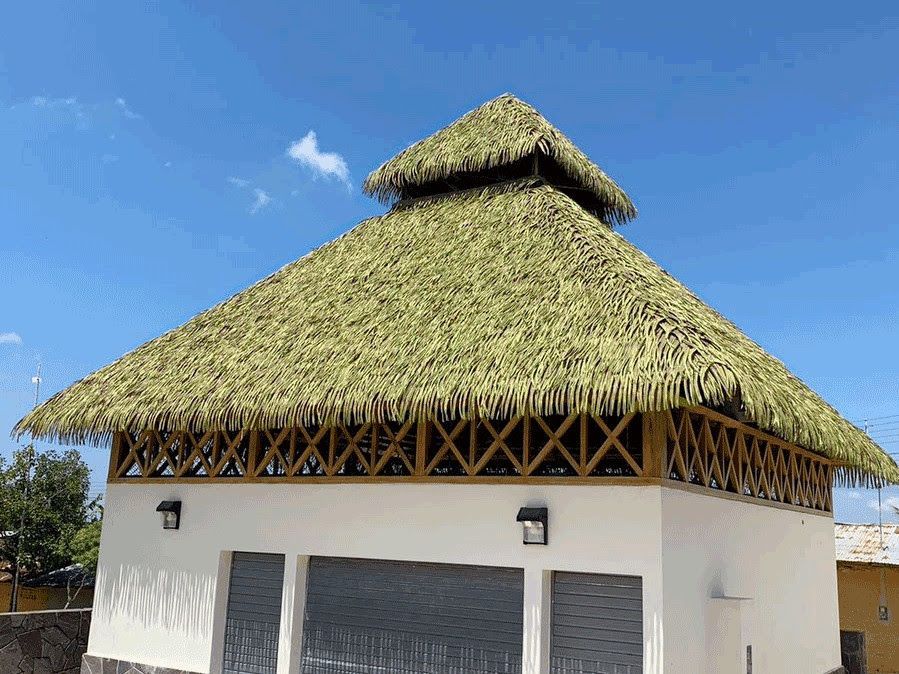 A white building with a thatched roof and a blue sky in the background.