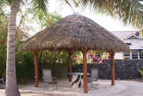 A thatched gazebo with a table and chairs underneath it
