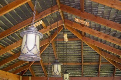 Three lanterns are hanging from the ceiling of a wooden structure.