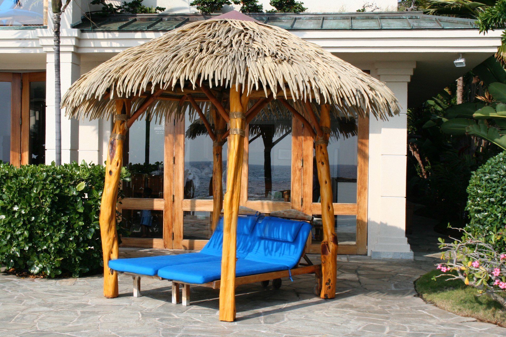 A gazebo with thatched roof sits in front of a house