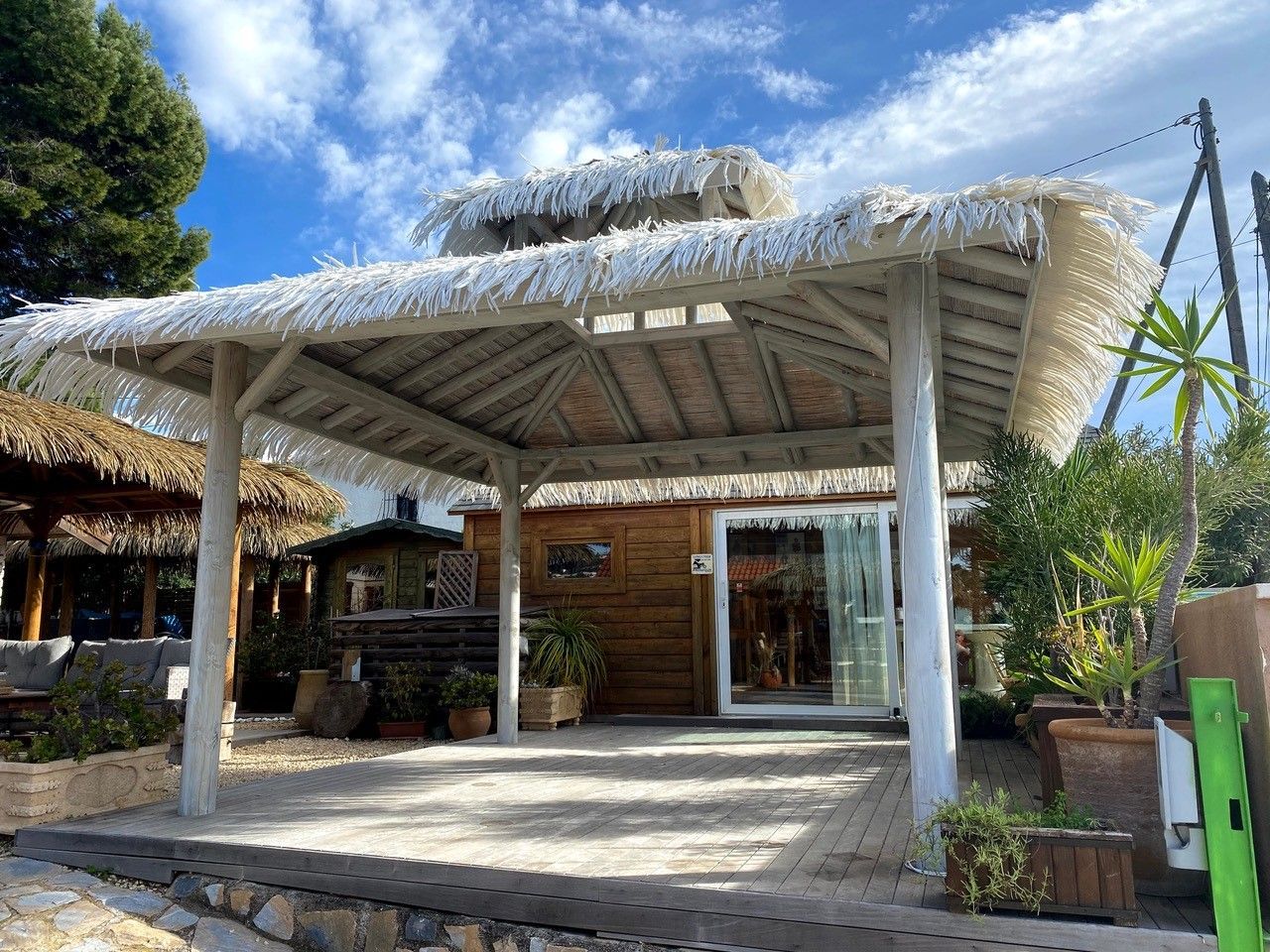 A wooden building with a thatched roof and a sliding glass door.