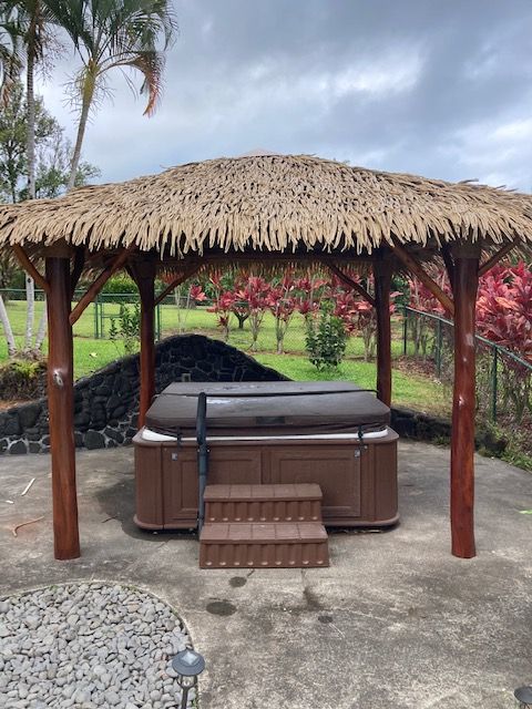 A thatched gazebo with a hot tub underneath it