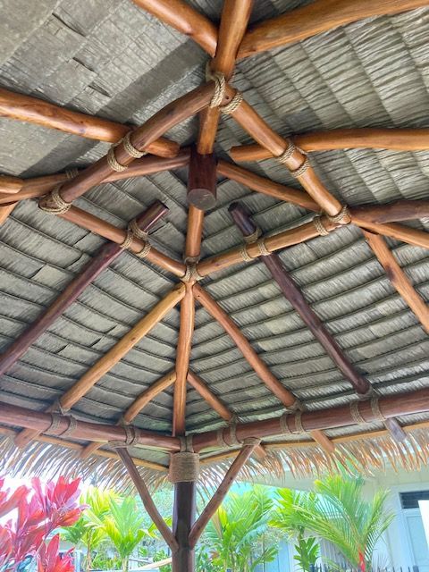 The ceiling of a gazebo made of wood and thatched roof.
