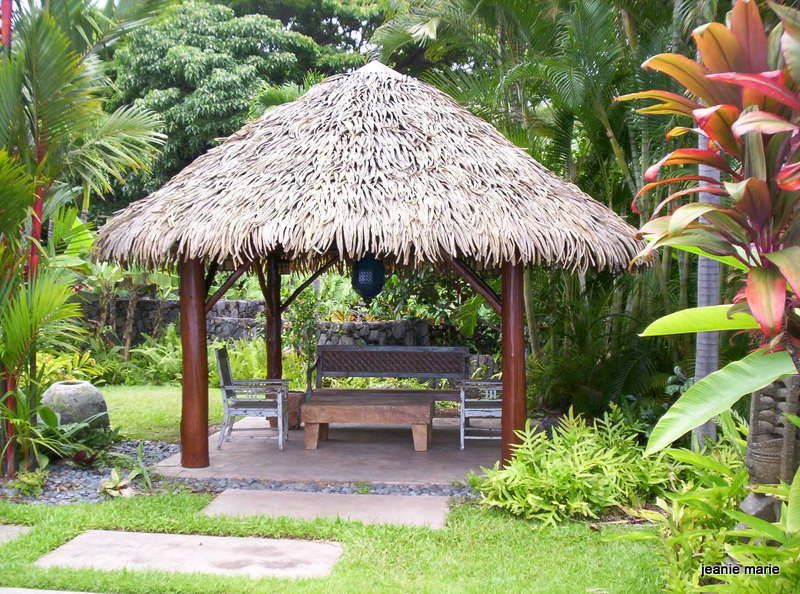 A thatched gazebo with a bench underneath it