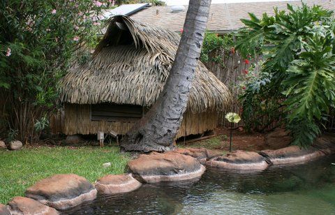A small hut with a thatched roof is sitting next to a pond.