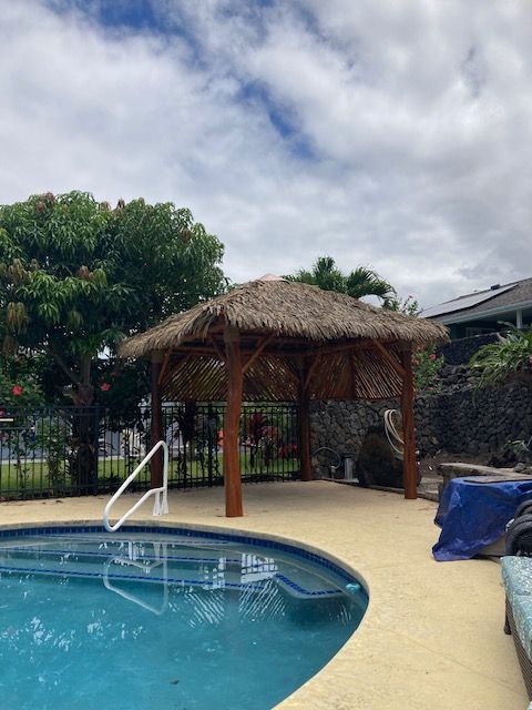 A swimming pool with a thatched gazebo in the background