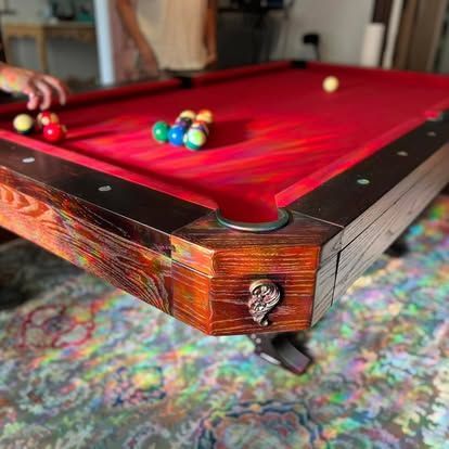 A person is playing pool on a pool table in a living room.
