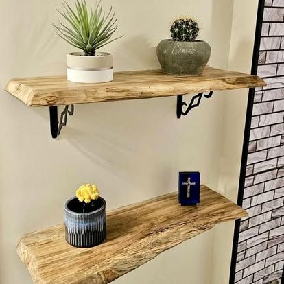 A wooden shelf with potted plants and a cross on it.