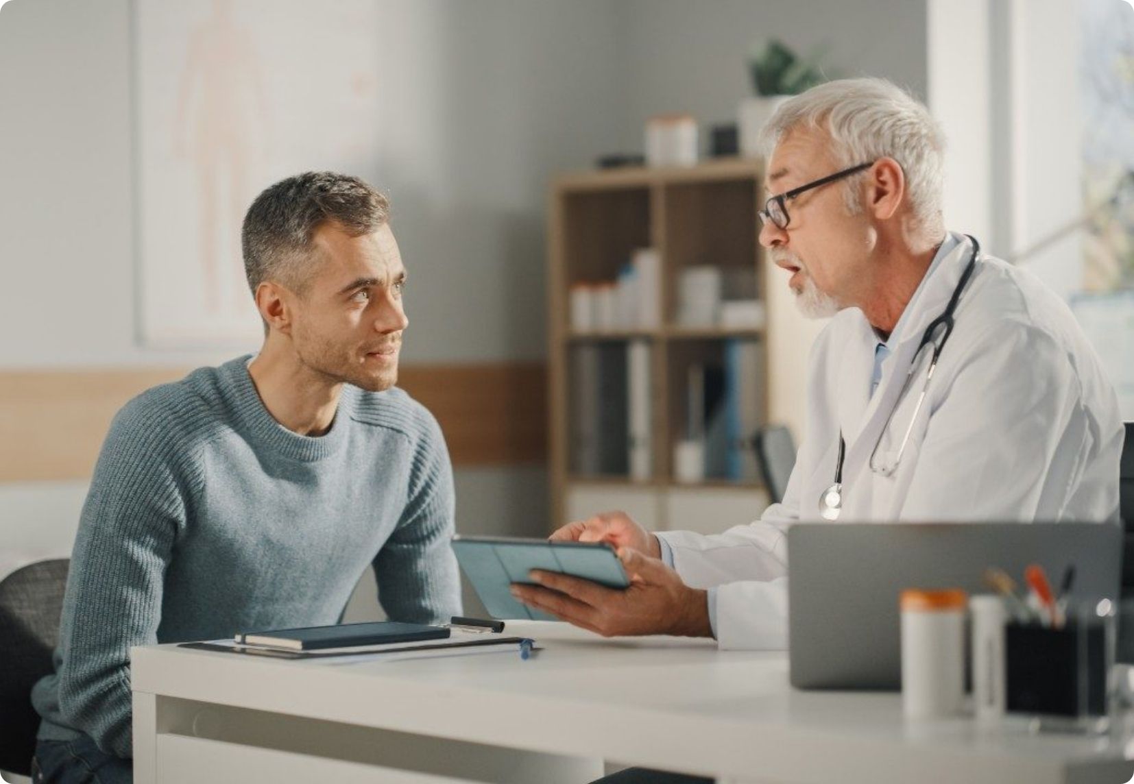 A professional consultation in an office as a doctor explains information on a tablet to a patient.