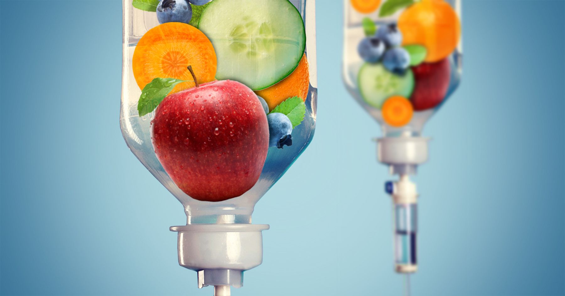 Two IV bags filled with various fresh fruits and vegetables against a solid blue background.