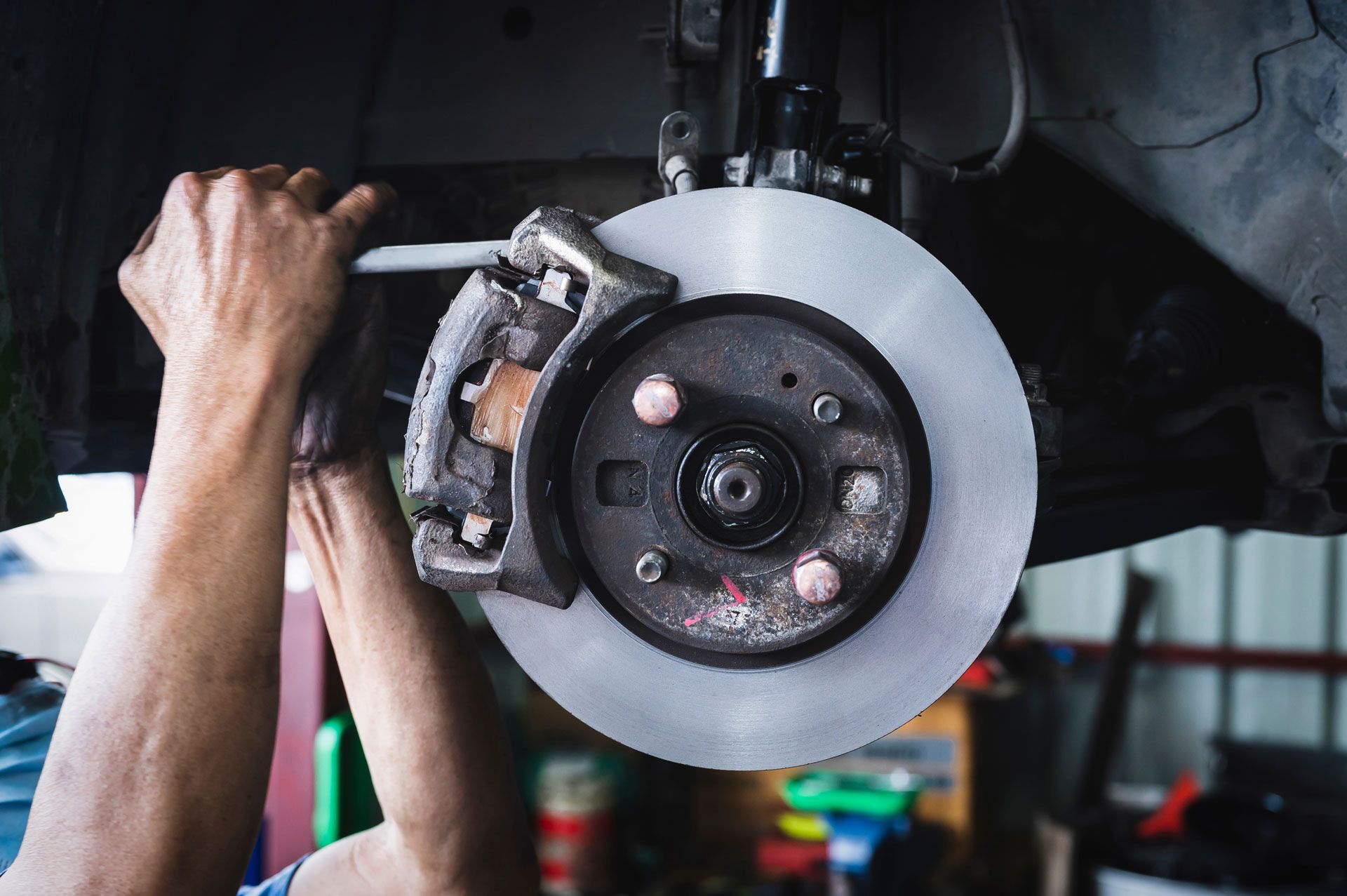 Mechanic replacing a car brake rotor and caliper in a garage