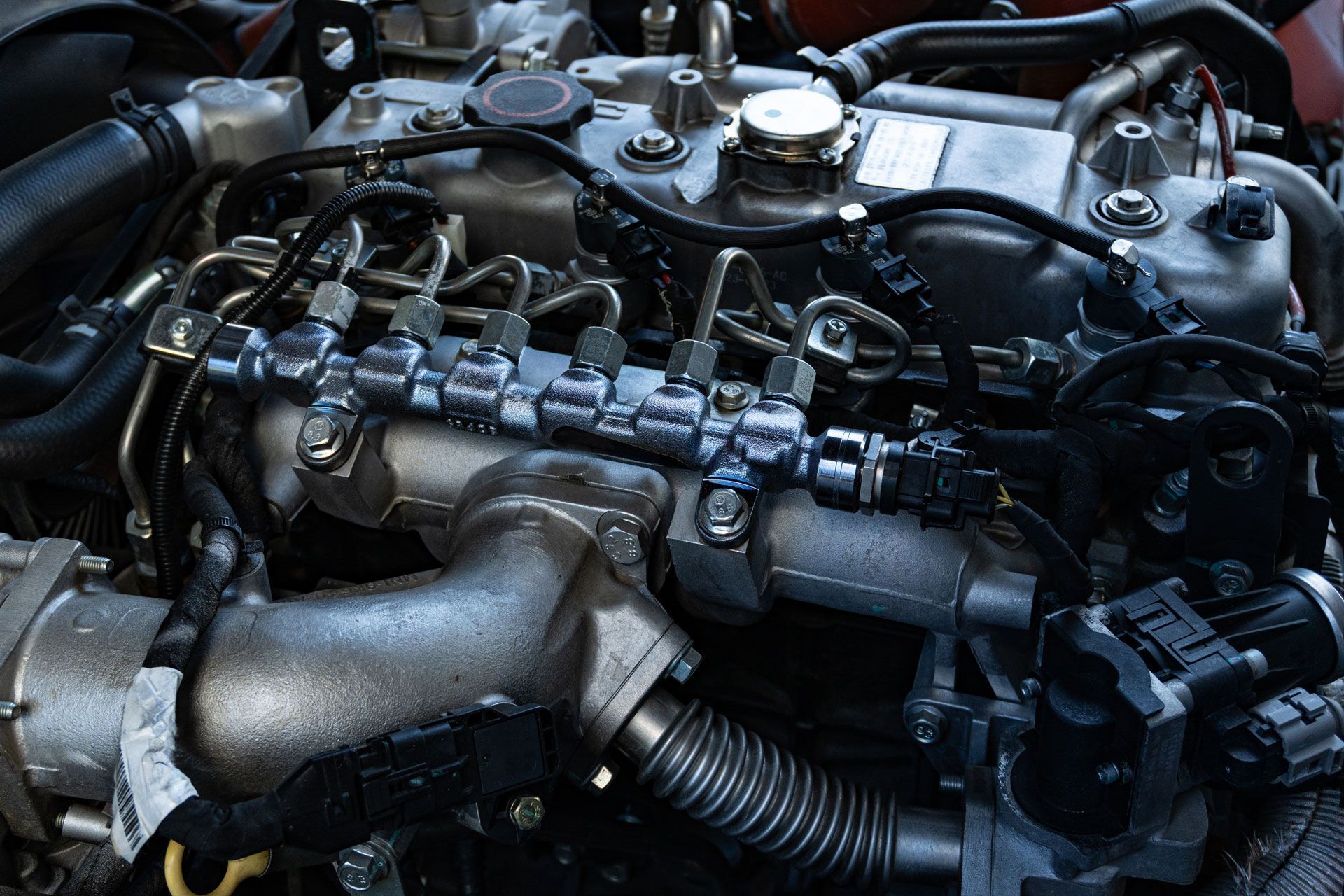 Close-up of a car engine with metal pipes, hoses, and components visible under the hood