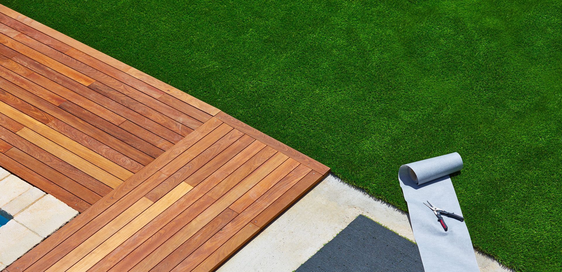 Artificial turf next to a wooden deck with materials to finish the turf