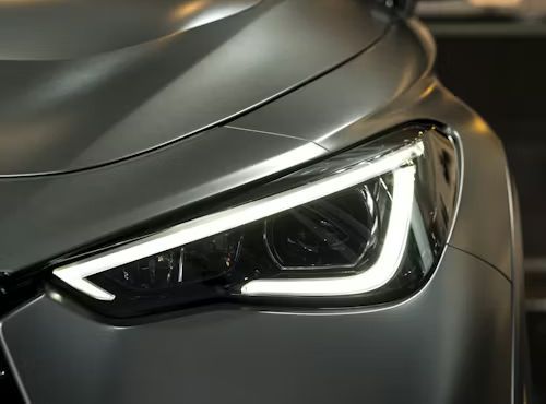 Close-up of a modern matte gray car’s sleek, illuminated LED headlight with a distinctive V-shaped daytime running light.