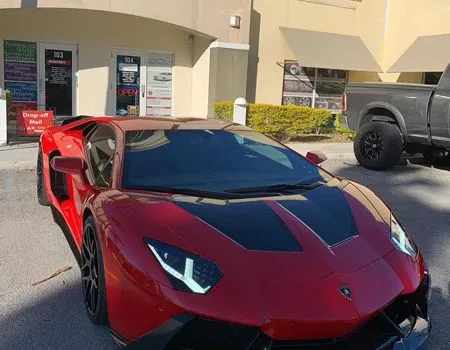 Red Lamborghini sports car parked outside a building on a sunny day