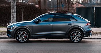 A blue audi q8 is parked on the side of the road.