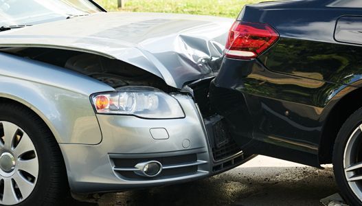 A silver car and a black car are involved in a car accident.