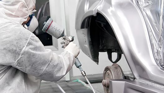 A man is spray painting a car in a paint booth.