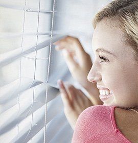 A girl looking through blinds