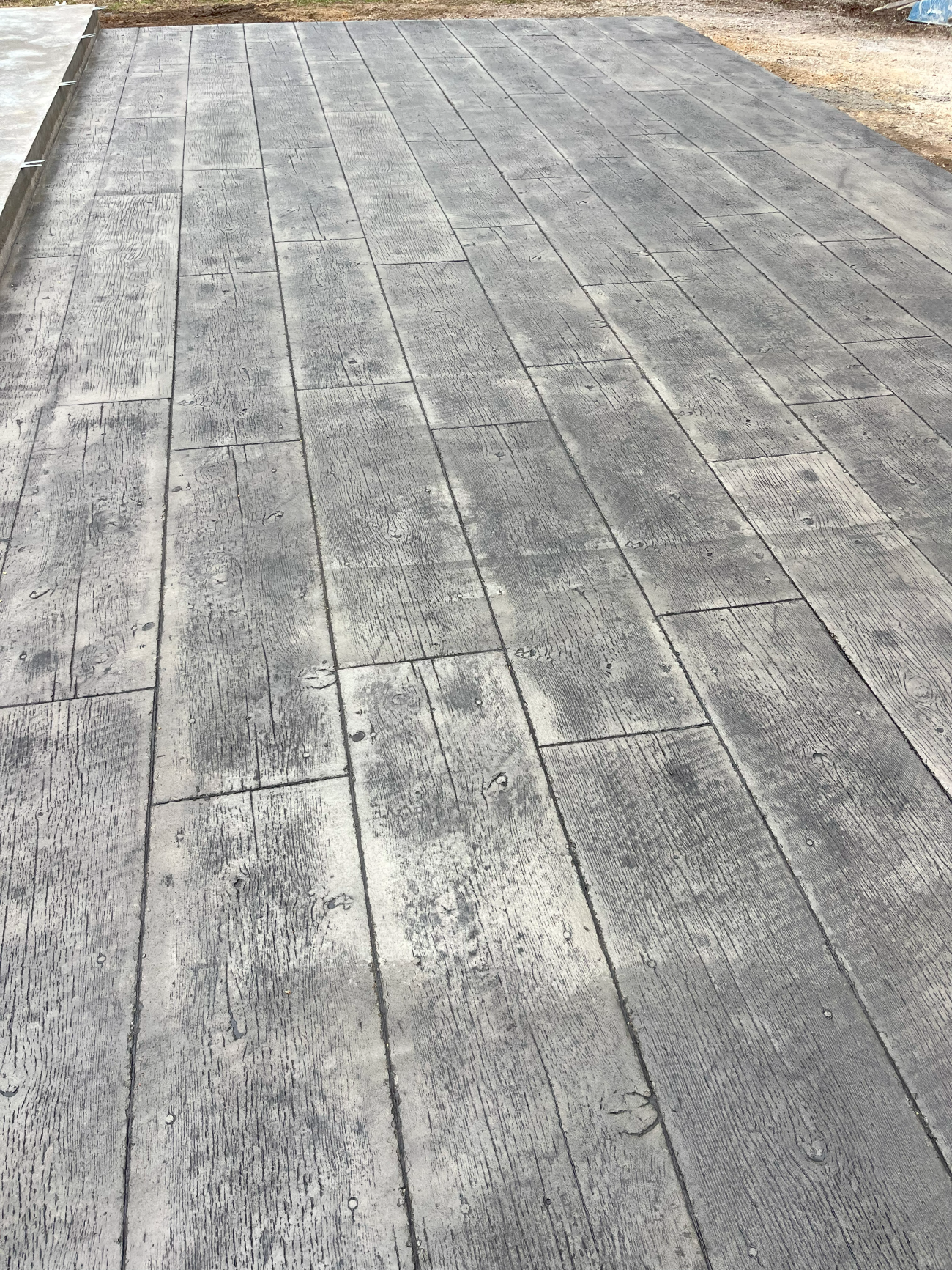 Gray stamped concrete patio with a wood plank pattern.