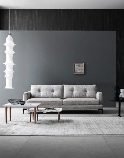 Divano chiaro e tavolini bianchi con gambe in legno