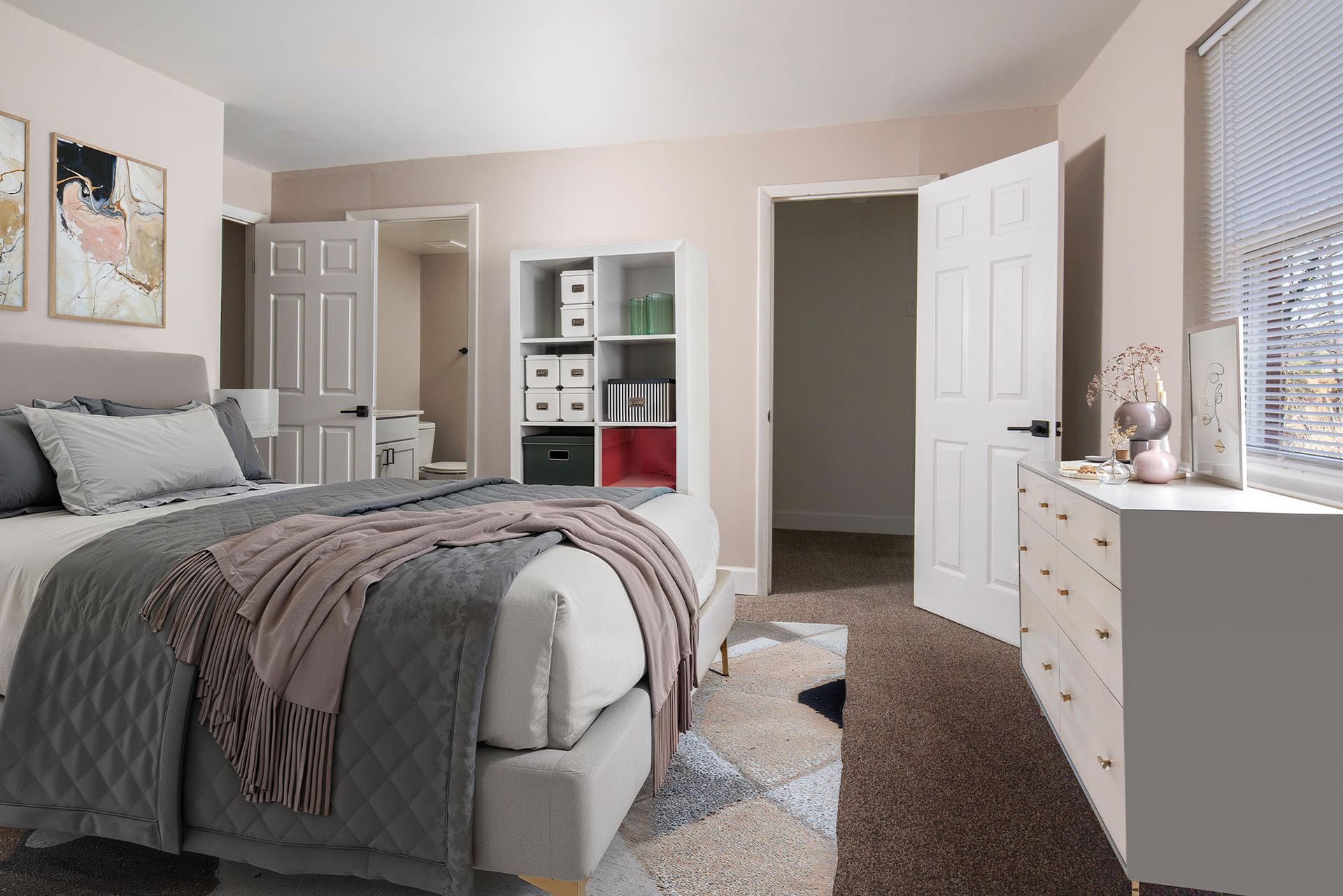 Bedroom of an apartment with a bed, dresser, and open cubby storage unit.