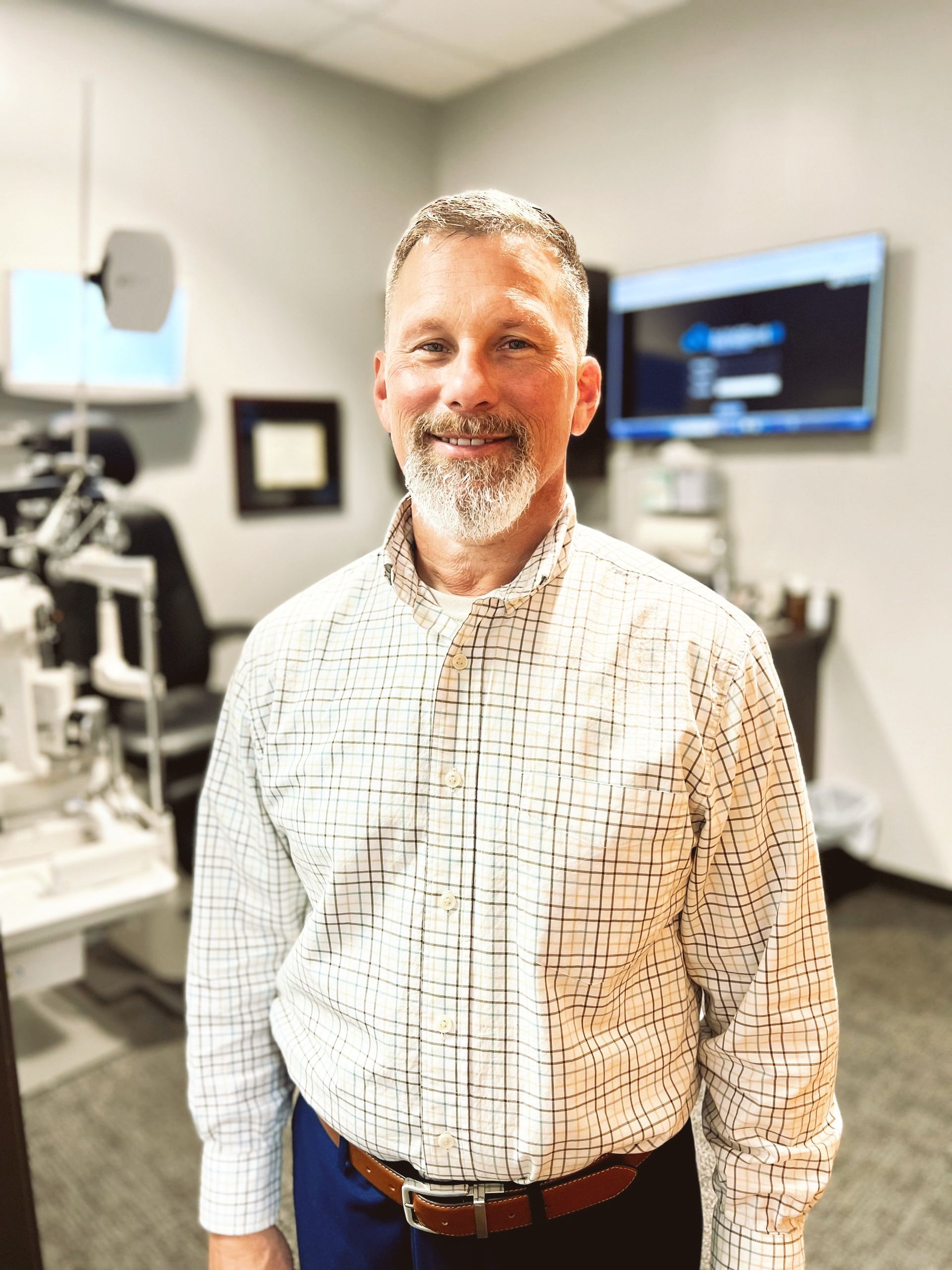 A man with a beard is standing in an ophthalmologist 's office.