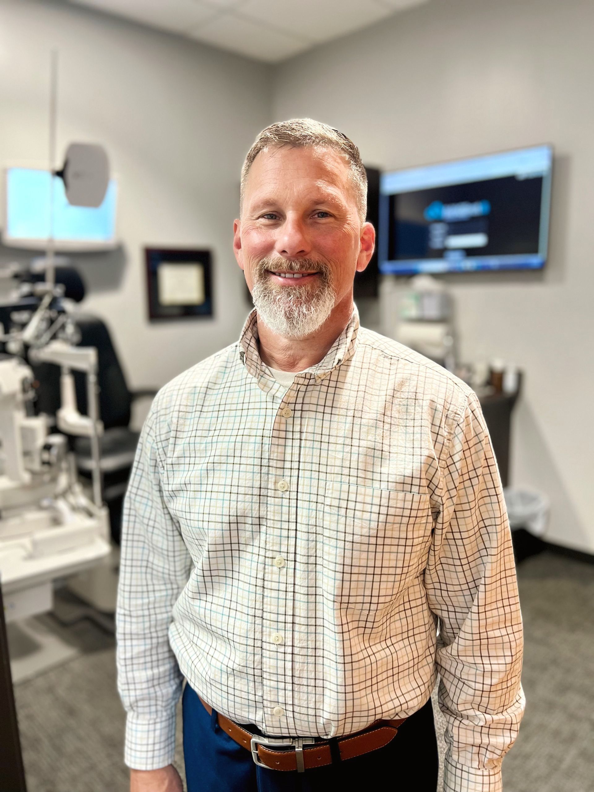 A man with a beard is standing in an ophthalmologist 's office.