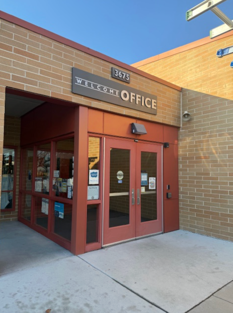Entrance to an office building with red doors and brick exterior. Sign reads 